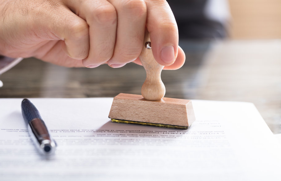 Hand stamping a certifcation onto a piece of paper