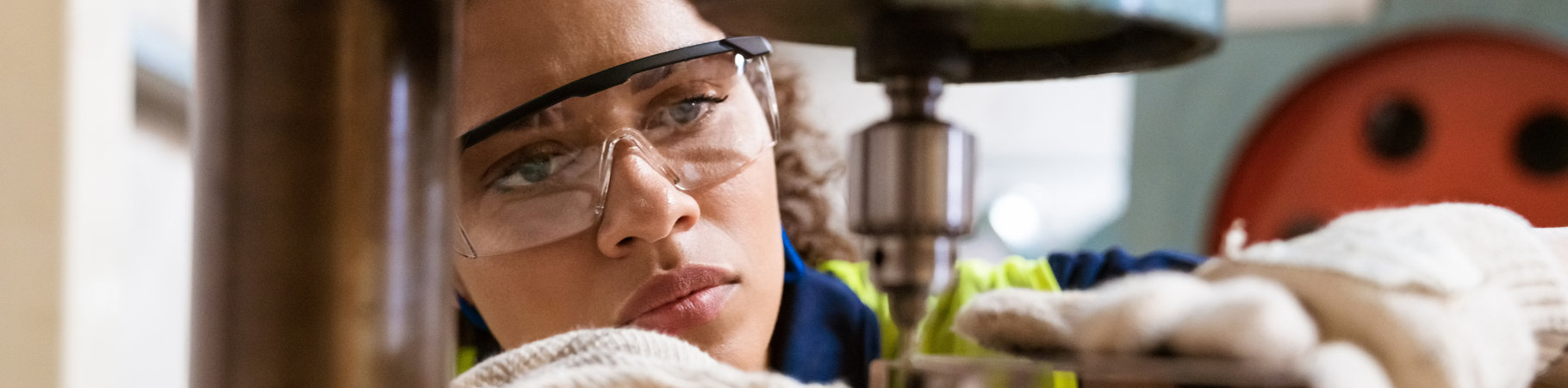 Woman wearing safety gear and using a precision drill