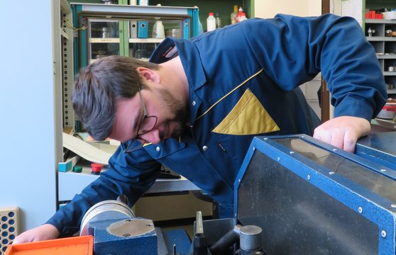 Man wearing glasses and blue jacket observing machine processes